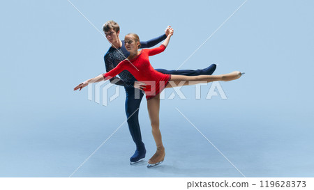 Male and female figure skating partners perform synchronized routine, showcasing their balance and athleticism against cold blue background. 119628373