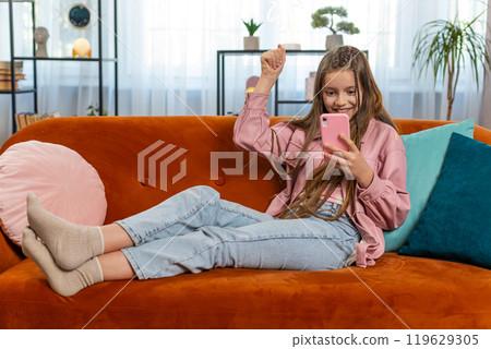Happy girl child kid using mobile smartphone celebrate online game win good positive news at home 119629305