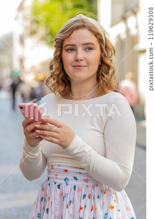 Young woman using smartphone typing text messages looking for a way on map in mobile navigator app 119629308