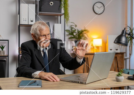 Senior businessman working on laptop at home office desk talk on online communication video call Senior businessman working on laptop at home office desk talk on online communication video call 119629377
