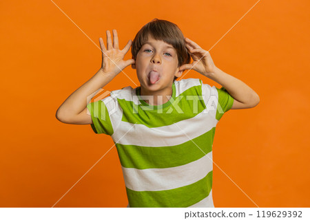 Cheerful funny bully child boy showing tongue making silly faces, fooling around, joking, teasing Cheerful funny bully child boy showing tongue making silly faces, fooling around, joking, teasing 119629392