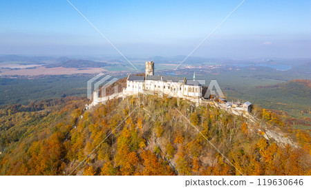This aerial perspective captures Bezdez medieval castle nestled on a hill, surrounded by vibrant autumn foliage. The landscape showcases the natural beauty of the season. 119630646