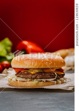 Juicy cheeseburger with fresh vegetables and melted cheese on sesame bun, fast-food lovers Juicy cheeseburger with fresh vegetables and melted cheese on sesame bun, fast-food lovers 119630659
