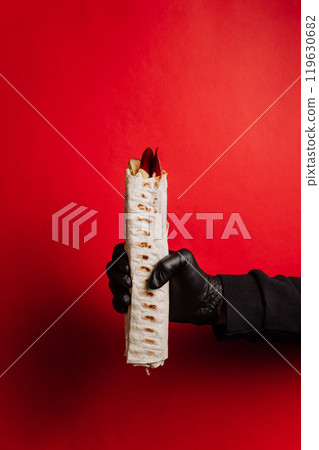 Minimalist shot of hand-held wrap on a bold red background, perfect for food branding and marketing Minimalist shot of hand-held wrap on a bold red background, perfect for food branding and marketing 119630682
