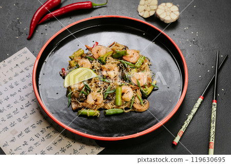 Stir-fried chicken with vegetables and glass noodles, garnished with sesame seeds for a healthy meal 119630695