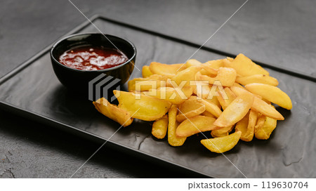 Crispy potato wedges served with ketchup, perfect snack or side dish for any meal 119630704