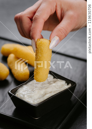 Dipping crispy cheese stick into creamy sauce. Perfect snack for cheese lovers and party appetizers 119630706