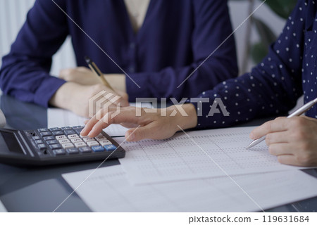 Two unrecognizable accountants or auditors reviewing financial documents in office. Audit and taxes Two unrecognizable accountants or auditors reviewing financial documents in office. Audit and taxes 119631684