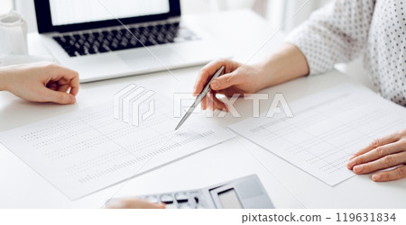 Accountant using a calculator and laptop computer for counting taxes with a client or a colleague at white desk in office. Teamwork in business audit and finance 119631834