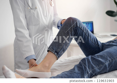 Doctor and patient are at the medical inspection in clinic. Orthopedic examines the knee of a young woman. Medicine concept Doctor and patient are at the medical inspection in clinic. Orthopedic examines the knee of a young woman. Medicine concept 119631903