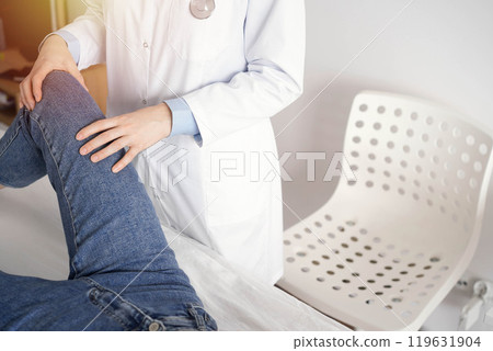 Doctor and patient are at the medical inspection in clinic. Orthopedic examines the knee of a young woman. Medicine concept 119631904