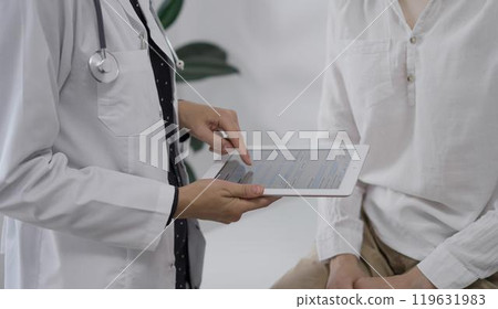 Doctor and a patient. The female physician is pointing into tablet computer besides a young woman during a consultation in the clinic. Medicine concept 119631983
