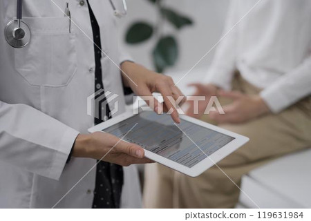 Doctor and a patient. The female physician is using a tablet computer besides a young woman during a consultation in the clinic, view above. Medicine concept Doctor and a patient. The female physician is using a tablet computer besides a young woman during a consultation in the clinic, view above. Medicine concept 119631984