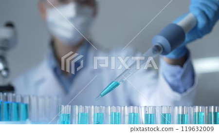 Close-up of a female scientist researcher hand using a micropipette to fill up test tubes with a blue liquid in laboratory setting. Medicine and science concept 119632009