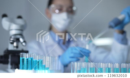 Laboratory tubes are in focus, closeup view. Female scientist researcher is using a micropipette at the background. Medicine and science 119632010