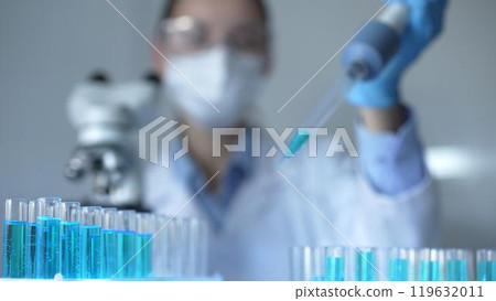 Close up of a female scientist researcher hand using a micropipette to fill up test tubes with a blue liquid in laboratory. Medicine and science Close up of a female scientist researcher hand using a micropipette to fill up test tubes with a blue liquid in laboratory. Medicine and science 119632011