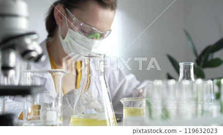 Woman scientist wearing protective gear is using digital tablet while working in a laboratory set, close up view. Science and medicine concepts Woman scientist wearing protective gear is using digital tablet while working in a laboratory set, close up view. Science and medicine concepts 119632023