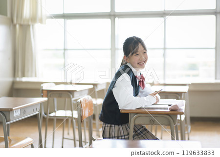 Smiling female junior high school student sitting in a classroom 119633833