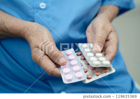 Asian elderly woman holding pill drug in hand, strong healthy medical concept. 119635369