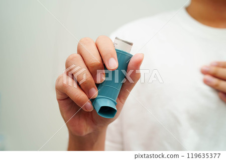 Asthma and chronic obstructive pulmonary disease COPD, Asian young man using metered dose inhaler MDI. 119635377