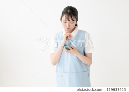 A woman in an apron worried about the phone A woman in an apron worried about the phone 119635613