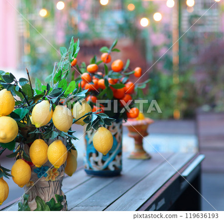 Branch with lemons, tangerines in ceramic vase on table. Traditional pattern, Sicily, Italy. Fruit and decor.  119636193