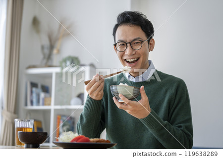 A man in his late 30s eating rice, looking at the camera A man in his late 30s eating rice, looking at the camera 119638289