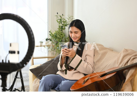 Smiling female vlogger checking phone and setting up for record a music video at home. Smiling female vlogger checking phone and setting up for record a music video at home. 119639006