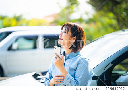 一位女士在汽車旁拿著智慧型手機 119639012