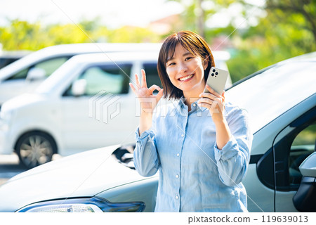 一位女士在汽車旁撥打智慧型手機 119639013