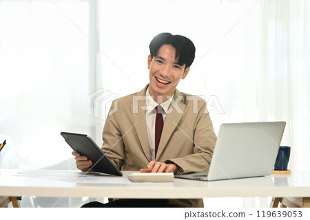 Cheerful young entrepreneur in formal suit working in modern workspace Cheerful young entrepreneur in formal suit working in modern workspace 119639053