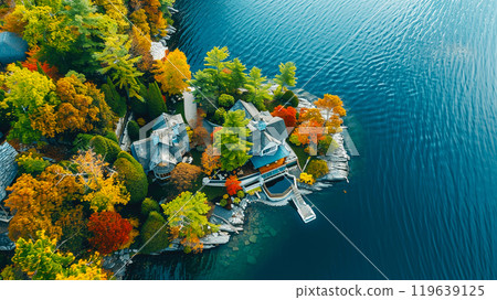 Aerial view of a beautiful lakeside house surrounded by vibrant autumn foliage and clear blue water. Aerial view of a beautiful lakeside house surrounded by vibrant autumn foliage and clear blue water. 119639125