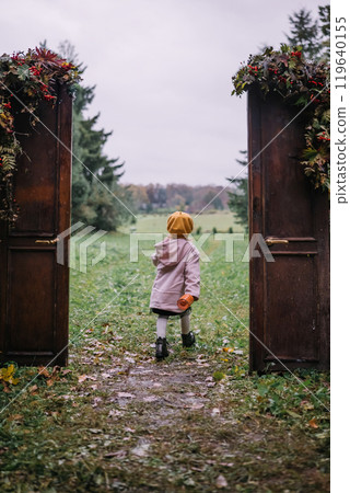 A child in a yellow hat walking through an open doorframe into a lush green field on a cloudy day A child in a yellow hat walking through an open doorframe into a lush green field on a cloudy day 119640155