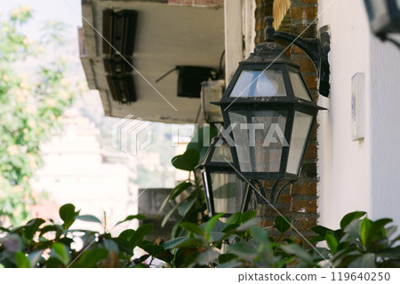 Classic lantern-style outdoor lighting and green plants 119640250