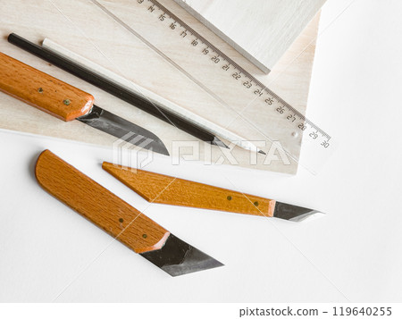 Crafting essentials. Precision knives, ruler, and pencil on wooden surface 119640255