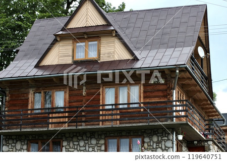 Three-story wooden beige house with complex roof structure. 119640751