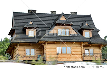 Three-story wooden beige house with complex roof structure. 119640752