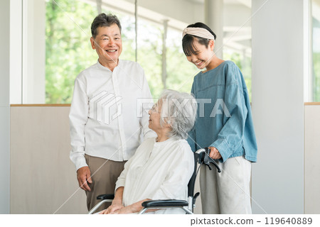 Granddaughter visiting a nursing home with grandmother and grandfather in wheelchairs (visiting, nursing home, nursing care, hospitalization, hospital) 119640889