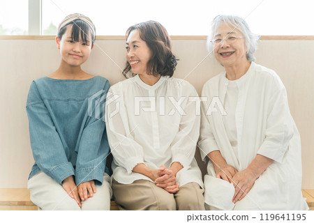 Three generations of parents and children (grandchild, mother, grandmother) sitting and talking 119641195