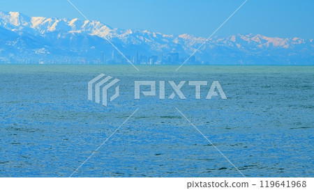 Skyscrapers On The Shore Of The Bay. Mountains Illuminated By The orange Rays Of The Rising Sun. Real time. Skyscrapers On The Shore Of The Bay. Mountains Illuminated By The orange Rays Of The Rising Sun. Real time. 119641968