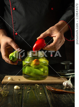 The concept of preserving bell peppers for long-term storage using a unique recipe. Chef holding red pepper in his hand in the kitchen The concept of preserving bell peppers for long-term storage using a unique recipe. Chef holding red pepper in his hand in the kitchen 119643470