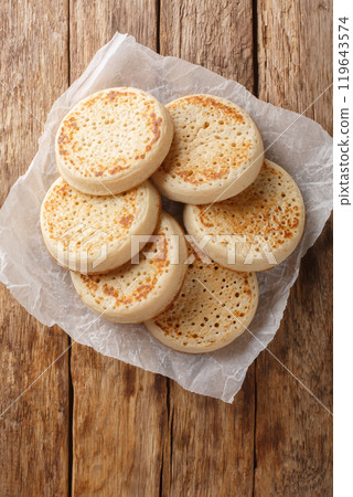 Freshly made English Crumpets close-up on parchment paper. Vertical top view Freshly made English Crumpets close-up on parchment paper. Vertical top view 119643574