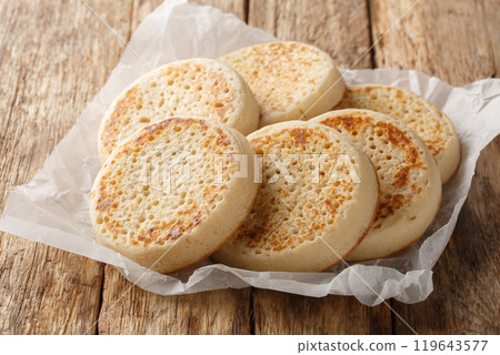 Porous Homemade English Crumpets close-up on parchment paper. Horizontal 119643577