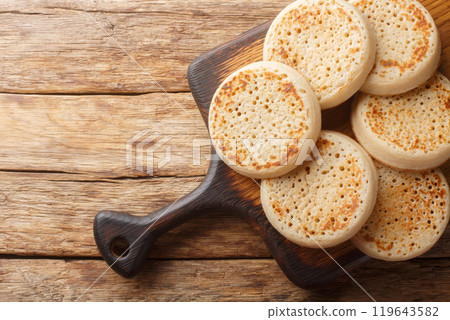 Close up of fresh golden crumpets on the wooden board. Horizontal top view 119643582