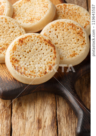 Crumpets fresh from a bakery closeup on the wooden board. Vertical Crumpets fresh from a bakery closeup on the wooden board. Vertical 119643587