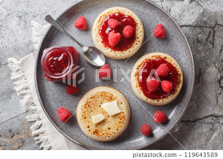 English style crumpets served with berries jam and butter closeup on the plate. Horizontal top view 119643589