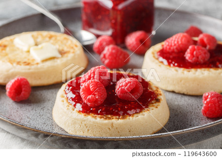British Crumpets breakfast with butter and raspberry jam closeup on the plate. Horizontal 119643600