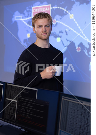 Confident male Cybersecurity Analyst with coffee cup in large Cyber Security Operation Center SOC handling Threats Confident male Cybersecurity Analyst with coffee cup in large Cyber Security Operation Center SOC handling Threats 119644305
