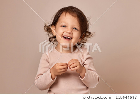 smiling child girl holding fruit pastille on beige background. healthy baby food. smiling child girl holding fruit pastille on beige background. healthy baby food. 119644688