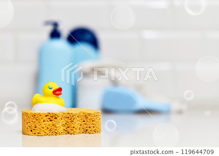 Yellow rubber duck, soap, bath foam on bath background, children bath accessories 119644709